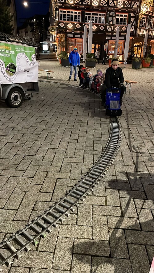 Mobile 5-Zoll-Bahn mit blauer Lok und roten Waggons im Einsatz bei einem Event, umgeben von Kindern und Familien. Perfekt für buchbare Veranstaltungen von QMZoller Amusement UG. Mobile 5-Zoll-Bahn mit blauer Lok und roten Waggons im Einsatz bei einem Event, umgeben von Kindern und Familien. Perfekt für buchbare Veranstaltungen von QMZoller Amusement UG.
