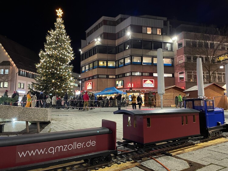 Die mobile 5-Zoll-Bahn im Stadtzentrum vor einem großen Weihnachtsbaum, ein Highlight für Familien und ein Hingucker bei Events, organisiert von QMZoller Amusement UG. Die mobile 5-Zoll-Bahn im Stadtzentrum vor einem großen Weihnachtsbaum, ein Highlight für Familien und ein Hingucker bei Events, organisiert von QMZoller Amusement UG.